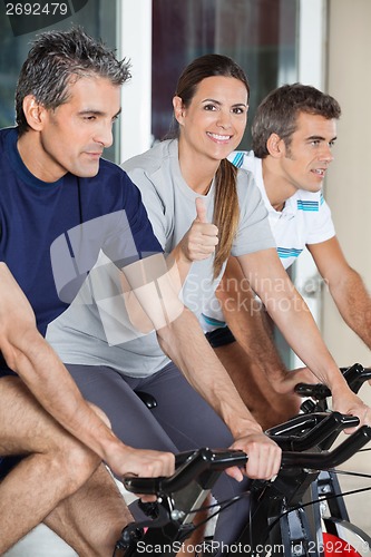 Image of Woman Showing Thumbs Up Sign While Exercising With Friends On Sp