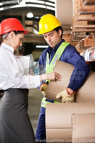 Image of Supervisor And Foreman Checking Cardboard At Warehouse