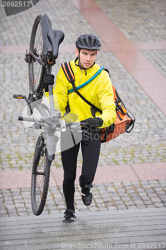 Image of Male Cyclist With Bicycle And Courier Bag Walking Up Steps