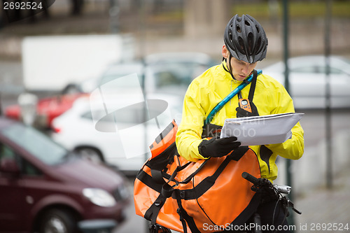 Image of Male Cyclist With Package And Courier Bag On Street