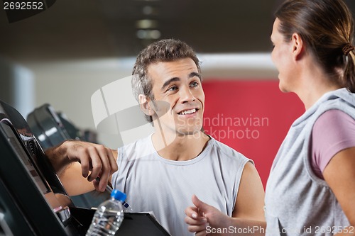 Image of Instructor Looking At Female Client Exercising On Treadmill