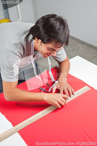 Image of Dressmaker Measuring Red Fabric
