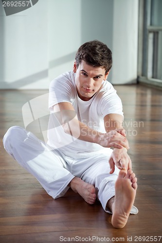 Image of Young Man Stretching Leg At Gym