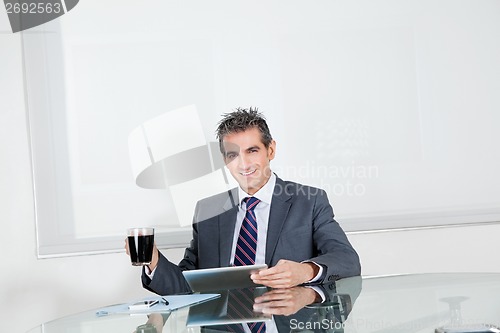 Image of Businessman With Coffee Cup Using Digital Tablet In Office