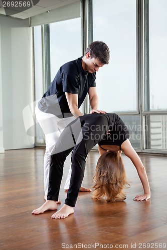 Image of Instructor Adjusting Woman's Yoga Posture