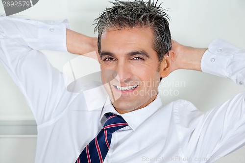 Image of Mid Adult Businessman Relaxing With Hands Behind Head