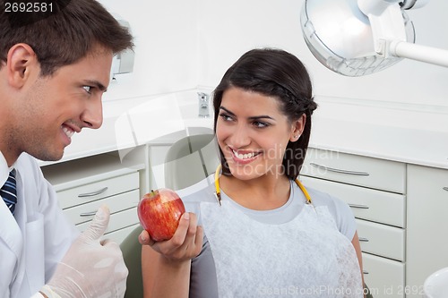 Image of Dentist Showing Thumbs Up Sign To A Female Patient Holding An Ap