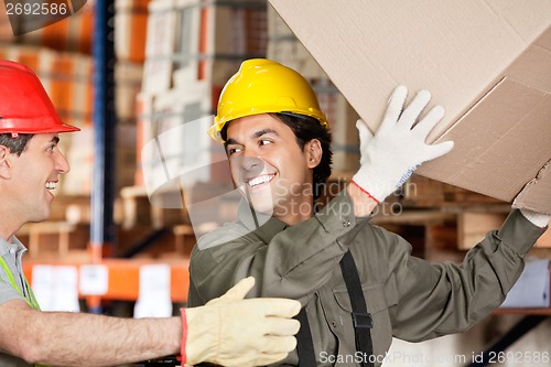 Image of Foreman With Coworker Lifting Cardboard Box At Warehouse