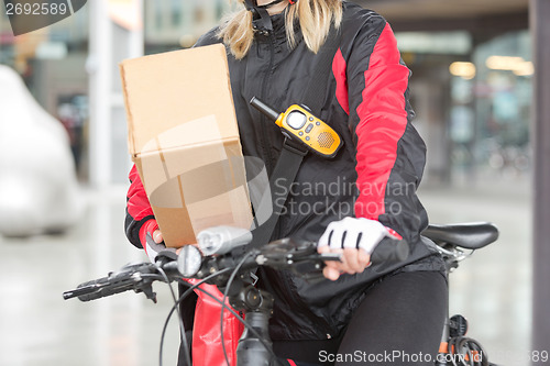 Image of Female Cyclist With Cardboard Box And Courier Bag On Street