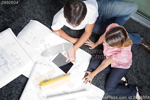 Image of Couple Sitting On Rug With House Plans