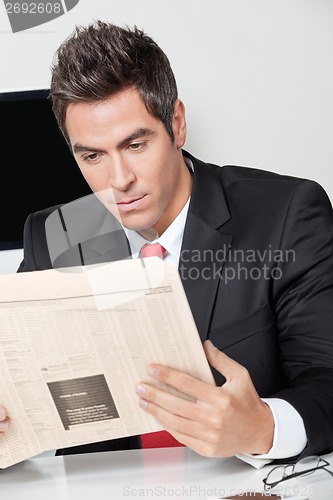 Image of Businessman Reading Newspaper In Office