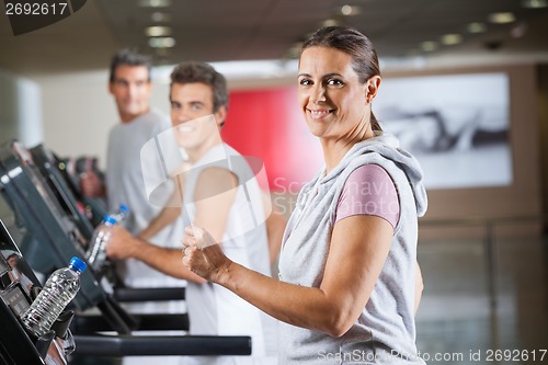Image of Woman And Men Running On Treadmill In Fitness Center