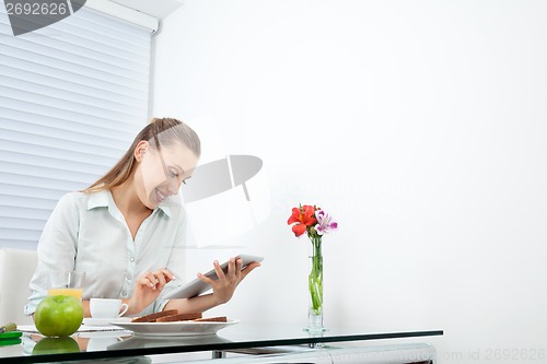 Image of Businesswoman At Breakfast Table Using Tablet PC