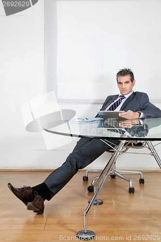 Image of Relaxed Businessman Using Digital Tablet In Office