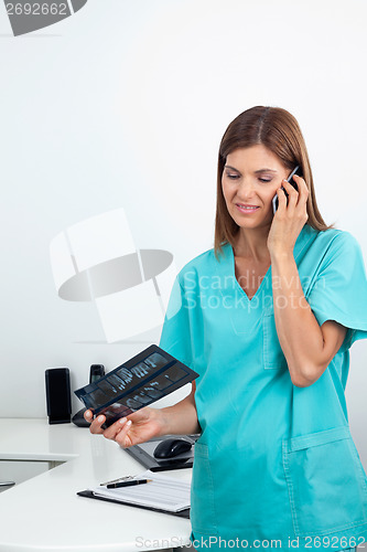 Image of Dentist With X-Ray Report Using Cellphone