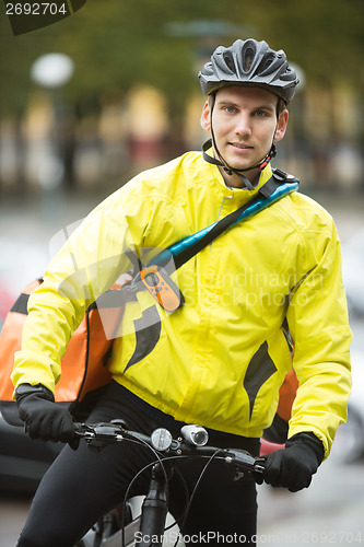 Image of Young Male Cyclist With Courier Delivery Bag On Street