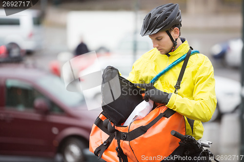 Image of Young Male Cyclist Putting Package In Courier Bag