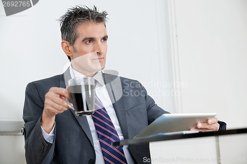 Image of Businessman With Coffee Cup Using Digital Tablet In Office