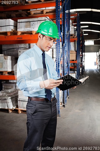 Image of Supervisor Reading Book At Warehouse