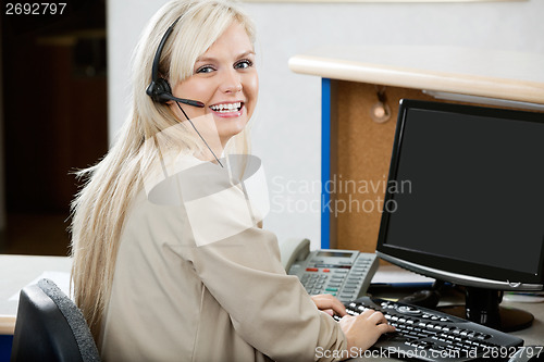 Image of Cheerful Woman Using Computer At Reception Desk