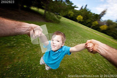 Image of Father Spinning Son Outdoors in Park