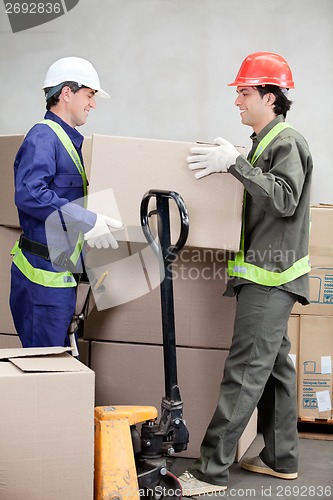 Image of Foremen Lifting Cardboard Box At Warehouse