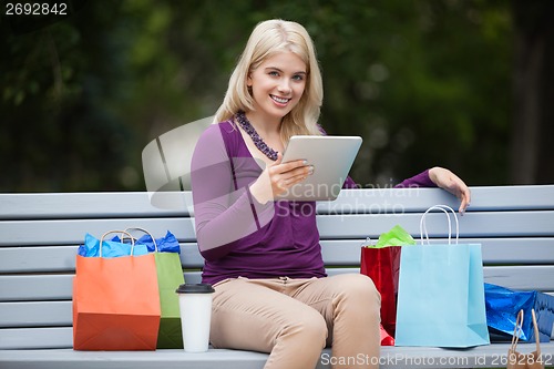 Image of Woman With Shopping Bags Using Tablet PC Outdoors