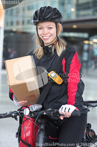 Image of Female Cyclist With Cardboard Box And Courier Bag On Street