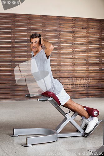 Image of Man Exercising On Machine In Health Club