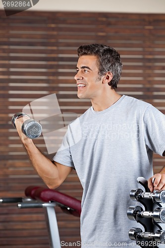 Image of Man Lifting Dumbbell In Health Center