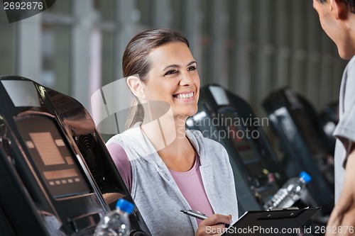 Image of Instructor Looking At Male Client Exercising On Treadmill