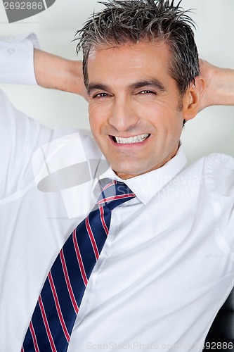 Image of Mid Adult Businessman Relaxing With Hands Behind Head