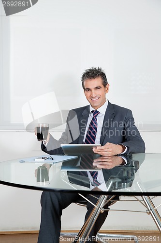 Image of Businessman With Coffee Cup Using Digital Tablet In Office