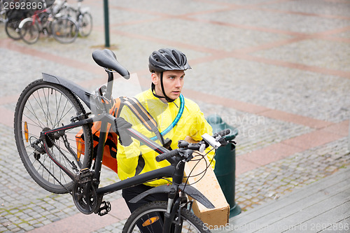 Image of Courier Delivery Man With Package And Bicycle Walking Up Steps