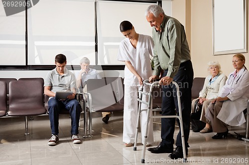 Image of Man Being Helped By Nurse To Walk Zimmer Frame