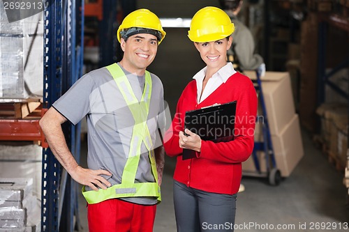 Image of Supervisor Holding Clipboard Standing With Foreman At Warehouse