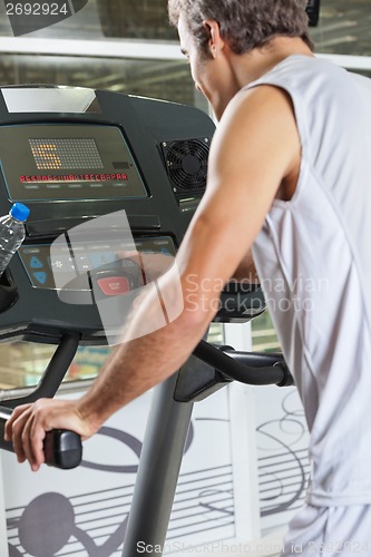 Image of Man Pressing Program Button on Treadmill