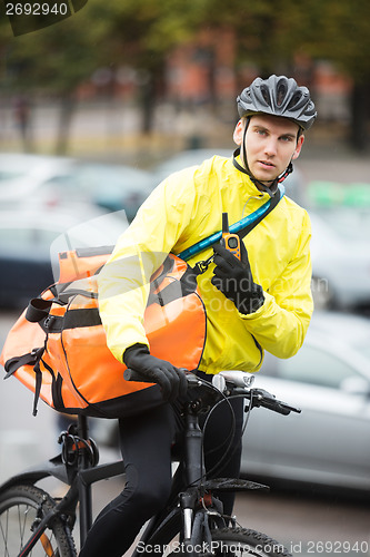 Image of Male Cyclist With Courier Bag Using Walkie-Talkie On Street