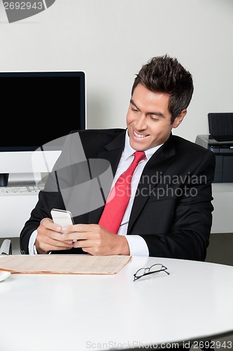 Image of Businessman Using Cell Phone At Desk