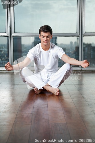 Image of Young Man Meditating On Wooden Floor