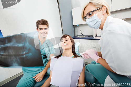 Image of Dentist With Female Assistant Showing X-Ray Image To Patient