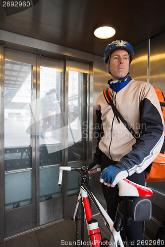 Image of Male Cyclist With Courier Bag Riding In An Elevator