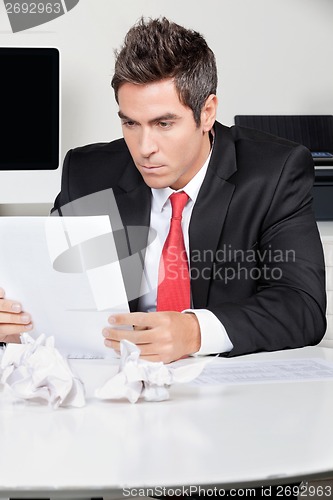 Image of Businessman Reading Document In Office