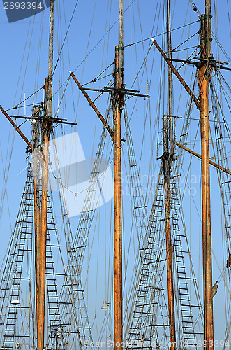 Image of wooden sailboat mast on blue sky