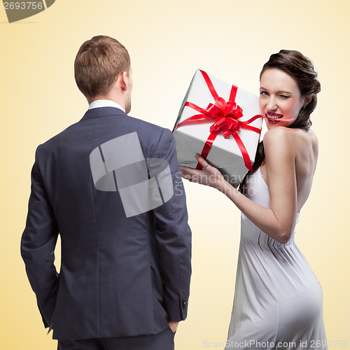 Image of Man looking on smiling woman holding gift