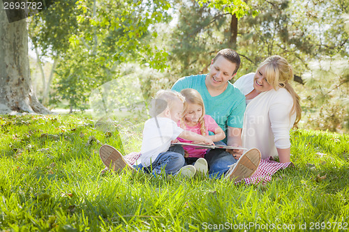 Image of Young Family Enjoys Reading a Book in the Park