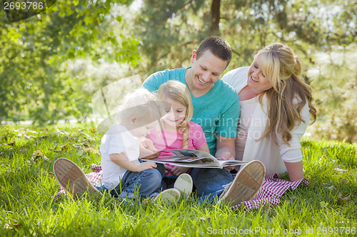 Image of Young Family Enjoys Reading a Book in the Park