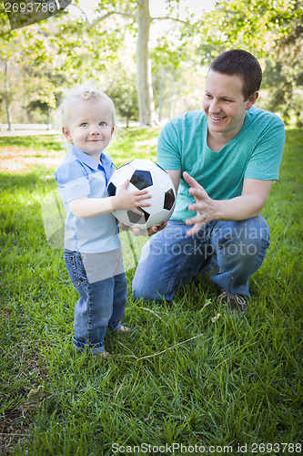 Image of Young Boy and Dad Playing with Soccer Ball in Park