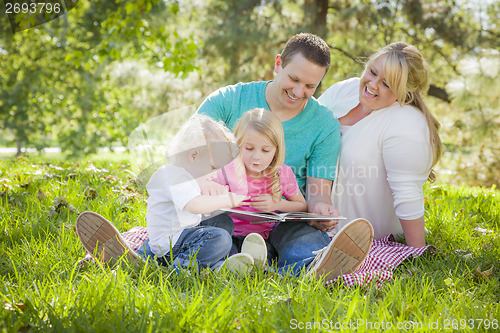 Image of Young Family Enjoys Reading a Book in the Park