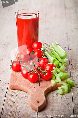 Image of tomato juice in glass, fresh tomatoes and green celery 